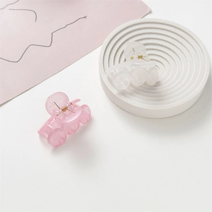 Detalle de pinzas para el cabello translúcidas rosa y blanco en plato de piedra decorativo