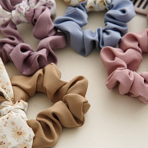 Detailed macro view of assorted floral and solid color pleated scrunchies set