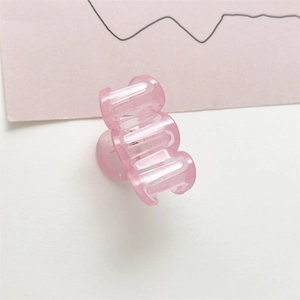 Detalle de la pinza para el cabello rosa translúcido con resorte de metal y dientes entrelazados