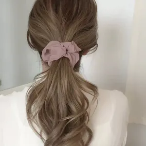 Détail d'un chouchou en maille rose porté sur une queue de cheval au style doux