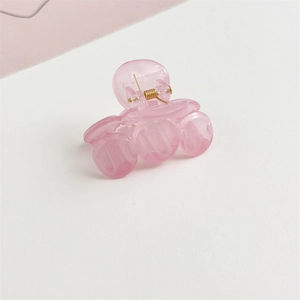 Vista detallada de una mini pinza de pelo rosa con muelle de metal dorado