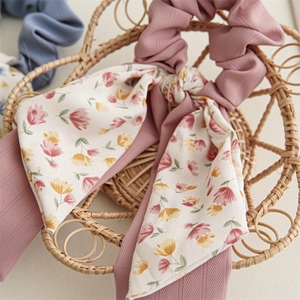 Detail of pink floral chiffon scrunchie with long ribbons on a rustic wicker basket