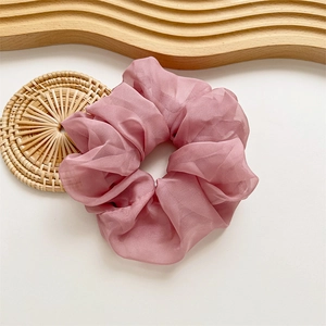 Gros plan du chouchou élégant en tulle rose poudré avec plis sur un plateau en bois