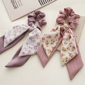 Detailed macro view of pink and purple floral scrunchies with long ribbons on stone