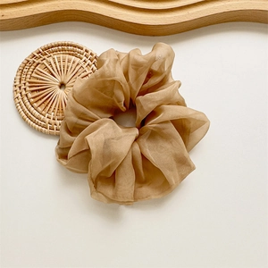 Gros plan d'un chouchou géant en organza caramel avec texture naturelle sur un plateau en bois