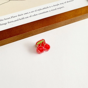 Détail d'une petite pince à cheveux cerise rouge avec feuilles et lettrage blanc