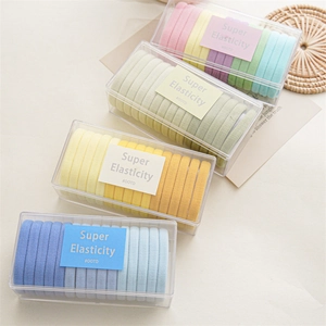Detalle de cuatro cajas coloridas con juegos de gomas para el pelo sin costuras elásticas