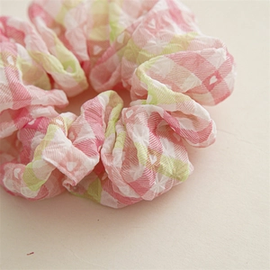 Vue détaillée des chouchous à carreaux rose et vert avec texture seersucker et cœurs