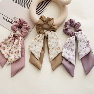 Close-up of three floral fabric bow scrunchies with long ribbons in soft pastel colors