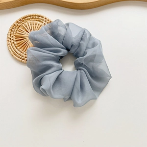 Gros plan d'un chouchou en maille bleu gris montrant sa texture plissée et son tissu organza