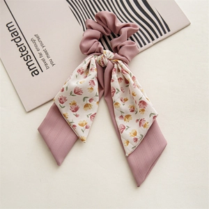Detailed texture of pink floral chiffon bow scrunchie with long ribbons on minimalist background