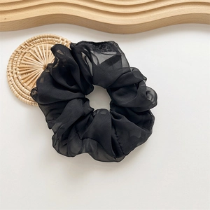 Détail d'un grand chouchou en maille noire transparente avec texture en mousseline douce