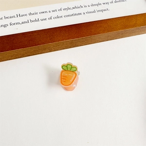 Vue détaillée d'une jolie pince à cheveux en forme de carotte orange avec feuilles vertes