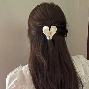 Dettaglio del fermaglio per capelli a cuore color crema su capelli castani per acconciature
