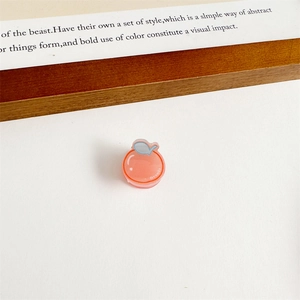 Gros plan d'une petite pince à cheveux orange en acrylique pour filles avec logo blanc