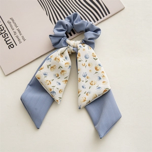 Detail of blue scrunchie with floral scarf ribbon on minimalist magazine background