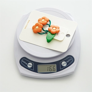 Détail de l'ensemble pince à cheveux fleur orange de 16,6g sur une balance électronique
