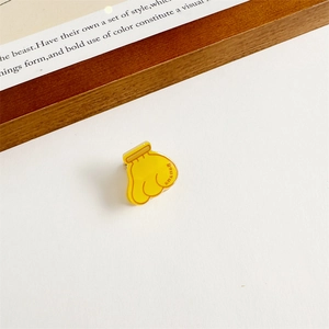 Gros plan sur une pince à cheveux banane en acrylique jaune avec motif dessin animé