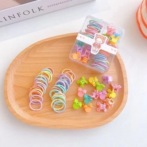 Détail de chouchous macarons colorés et mini-pinces dans une boîte transparente
