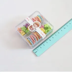 Détail d'élastiques macaron colorés et pinces à fleurs dans une boîte de rangement