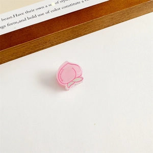 Détail d'une pince à cheveux pêche en acrylique rose avec texte Honey Peach et feuille