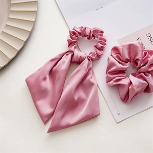 Detail view of pink satin scrunchies and ribbon ties set on an elegant magazine backdrop