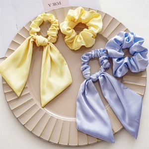 Detailed view of light yellow and blue satin hair scrunchies with elegant long ribbons