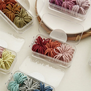 Detailed macro view of multi-colored elastic hair bands in a clear plastic storage box