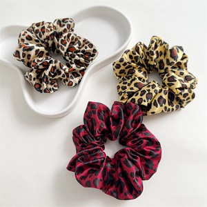 Detailed close-up of leopard print satin hair scrunchies set in three elegant colorways