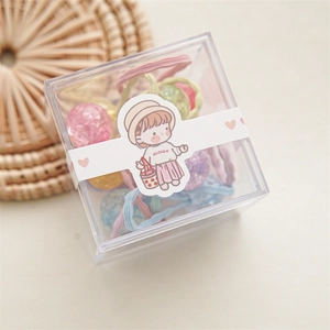 Détail d'élastiques à cheveux colorés dans une boîte transparente avec emballage dessin animé