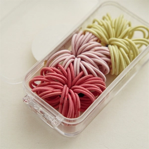 Detailed view of high-elasticity hair ties in red, pink and yellow with a storage box