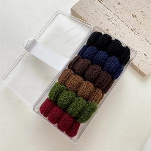 Detailed view of six thick seamless elastic hair ties in vintage forest tones in a clear box