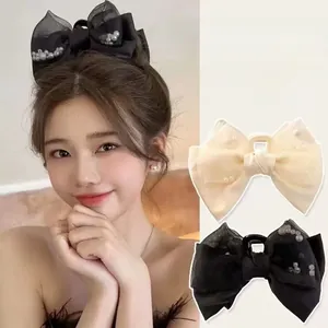 Detail of elegant black and white oversized bow hair clips with delicate pearl embellishments