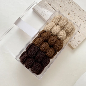 Detail of six seamless towel scrunchies in earth tones within a clear plastic storage box