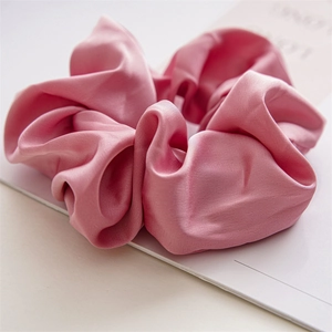 Macro detail of elegant light pink satin hair scrunchie with smooth silk texture and folds