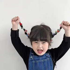 Close-up of colorful cartoon fruit hair ties and clips worn by a young child model