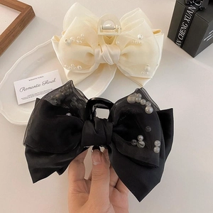 Close-up of black bow hair claw clip with faux pearls and elegant organza layers