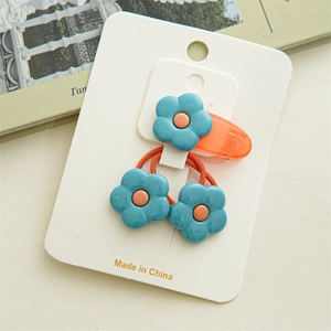 Détail de barrettes et élastiques à fleurs bleu et orange sur une carte de support
