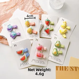 Close-up of cute fruit-themed kids hair clips including strawberry and pineapple designs