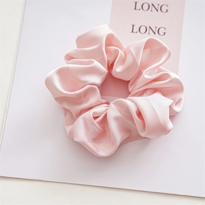 Detail shot of pink satin scrunchie with soft silk texture and elegant fabric folds