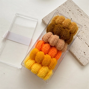Macro detail of elastic towel scrunchies in warm gradient colors stored in a transparent box