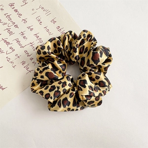 Detailed close-up of leopard print satin scrunchie with elastic pleated design and silky texture