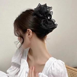 Détail d'une pince à cheveux élégante avec nœud en maille noire sur un chignon bas