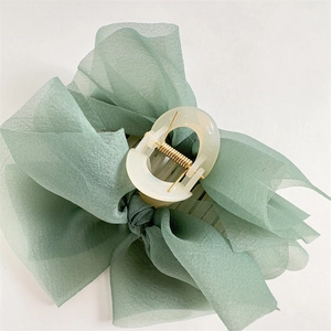 Dettaglio della molletta per capelli con fiocco in organza verde e molla dorata