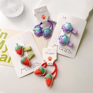 Detailed view of hand-embroidered strawberry and grape fabric hair accessories on cards