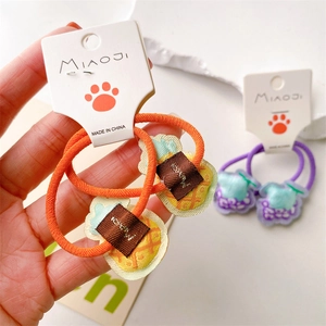 Detail of cute embroidered fruit hair ties featuring pineapple and grape charms