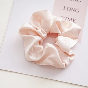 Detail of elegant oversized pale pink satin scrunchie with a soft silk texture and natural folds