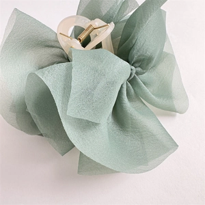 Dettaglio del fermaglio a fiocco verde menta con texture in organza a strati