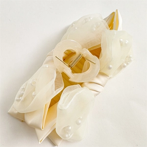 Detail of cream shark clip with satin organza ribbon and delicate white pearls