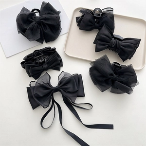 Detail showing five black bow hair clips in lace, mesh, satin, and polka dot chiffon fabrics